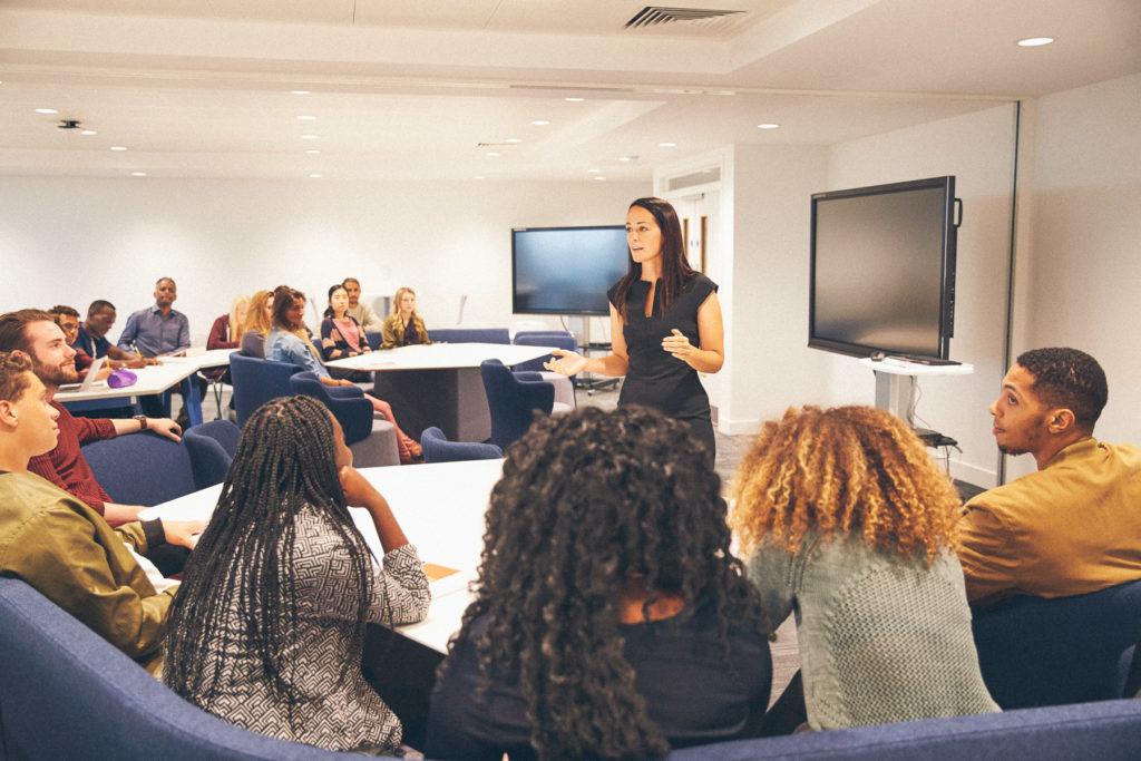 Female teacher addressing university students in a classroom